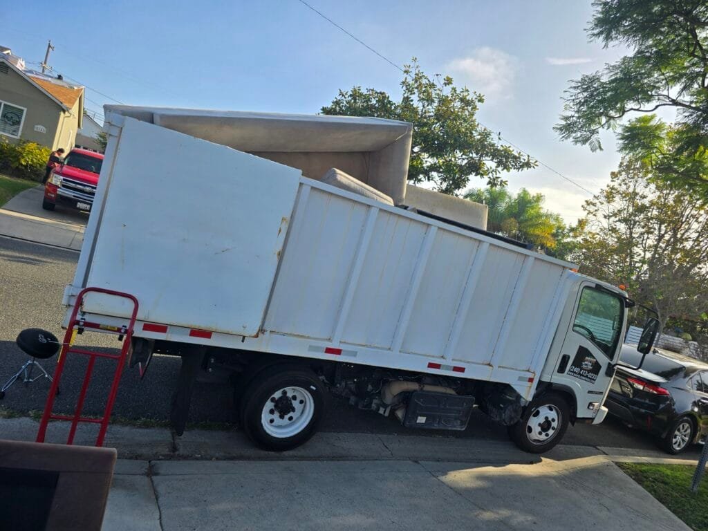 White box truck with a hand truck parked at the curb on a residential street