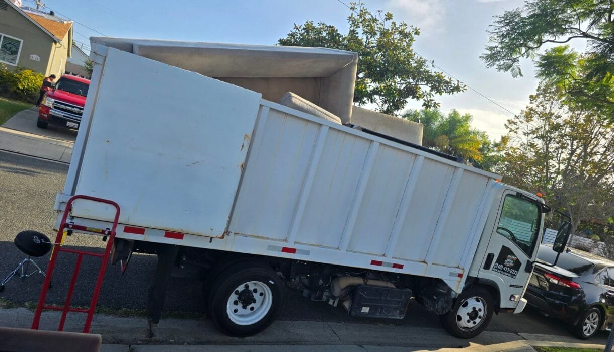 White box truck with a hand truck parked at the curb on a residential street