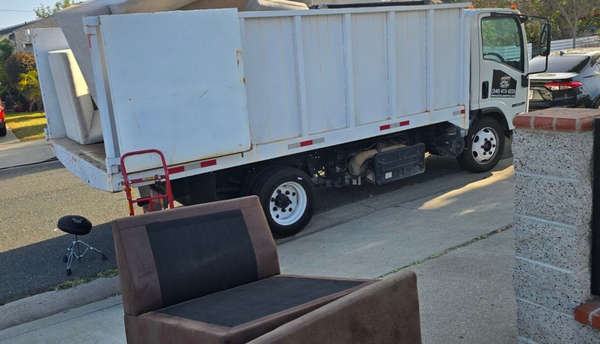Box truck parked at the curb with an armchair waiting to be loaded