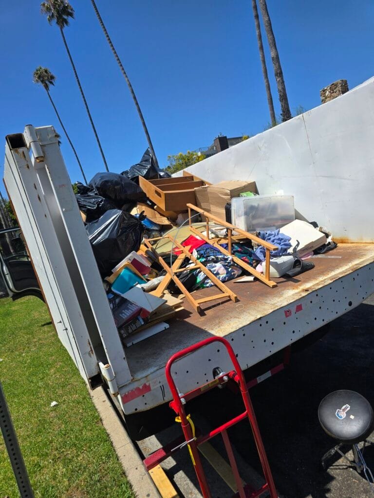 Truck bed loaded with wood furniture, boards and bags during a cleanout