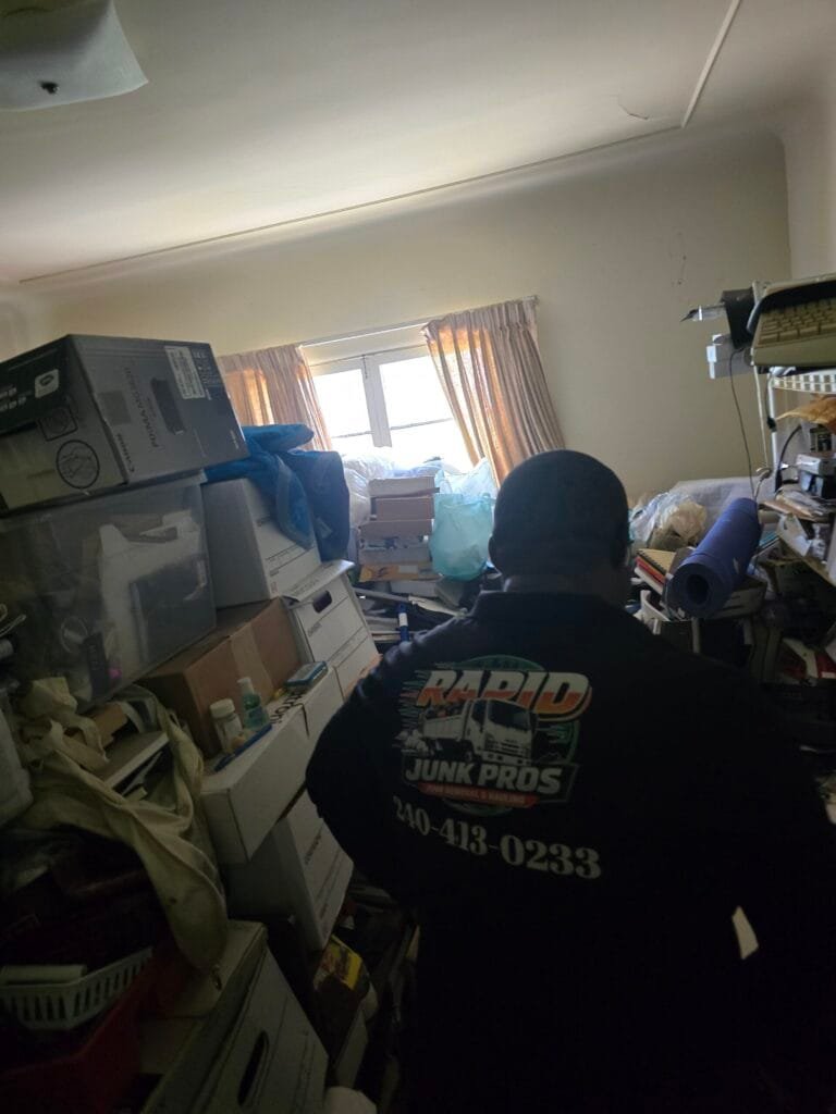 A Rapid Junk Pros crew member working in a room packed with boxes and stored items