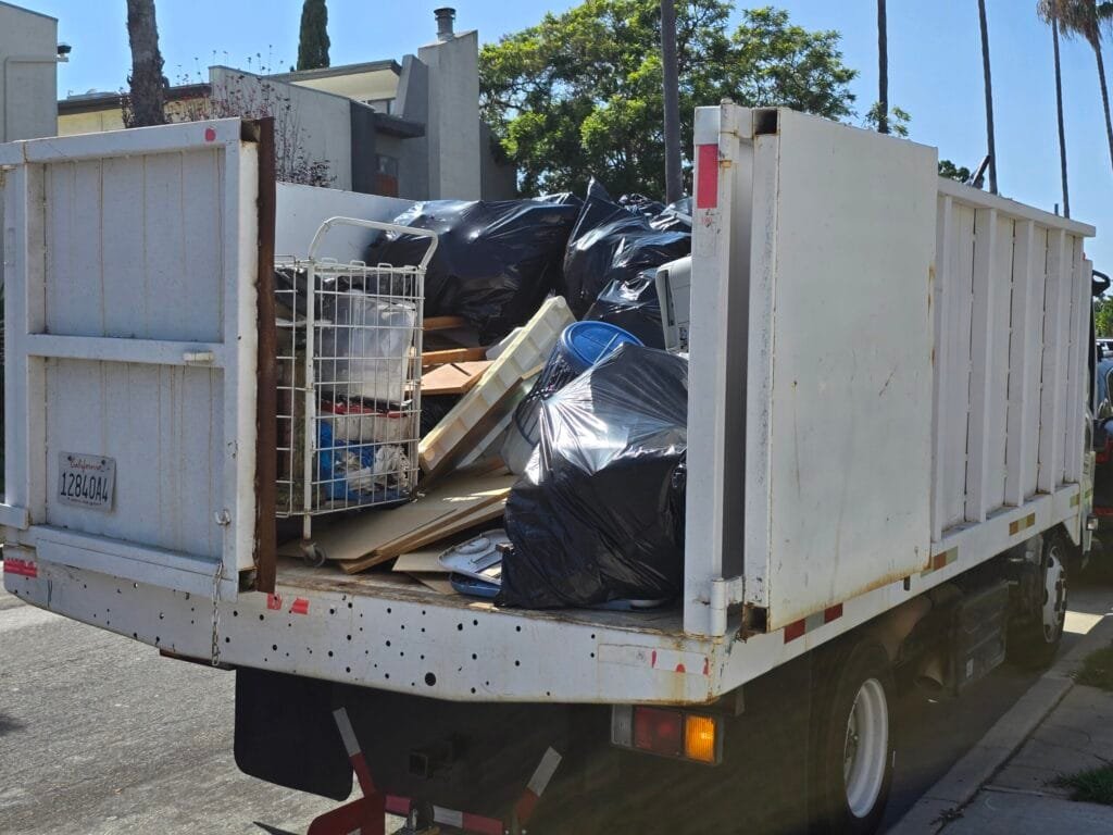 Box truck loaded with black trash bags, a wire basket and wood pieces after a cleanout