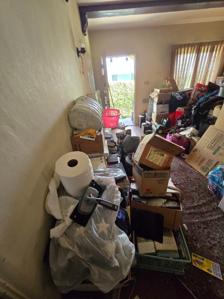 Hallway and room crowded with boxes, bags and household items before a cleanout