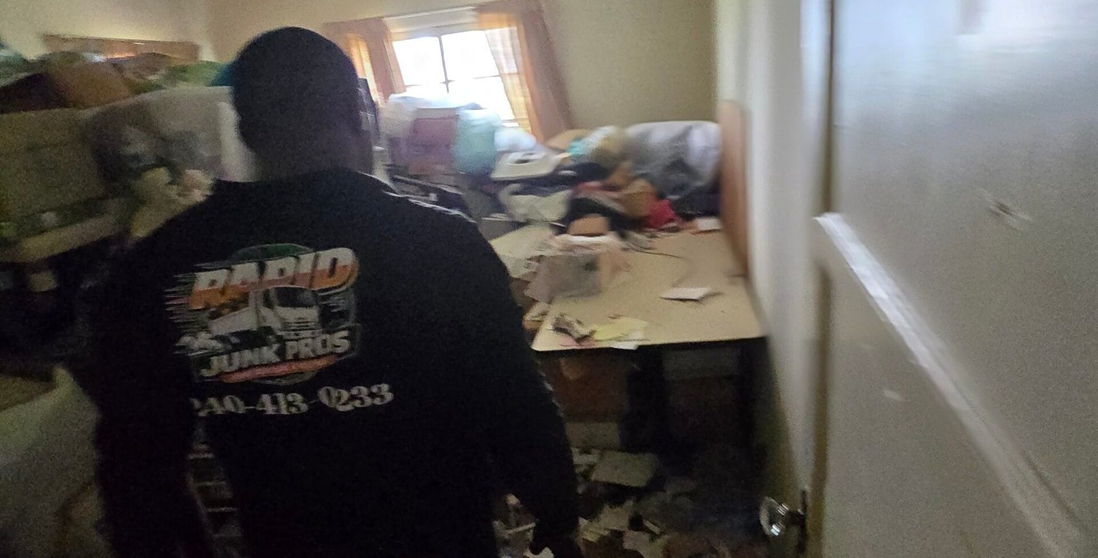 Rapid Junk Pros crew member walking into a cluttered room at the start of a cleanout